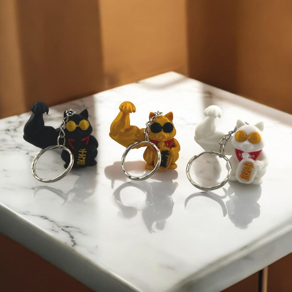 Super Buff Maneki Neko Keychain — 3D printed muscular lucky cat charm in gold, white, and black, made in Vancouver BC