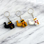 Super Buff Maneki Neko Keychain — 3D printed muscular lucky cat charm in gold, white, and black, made in Vancouver BC
