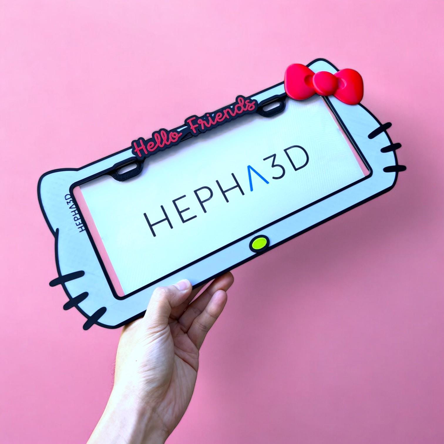 Hello Kitty x PopPlates — 3D printed kawaii license plate frame with bow and cat ear details, available in red and pink, made in Vancouver BC