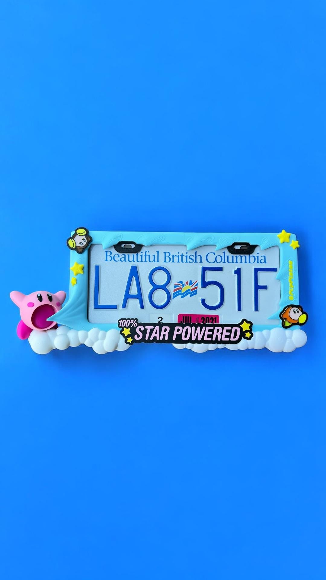 Kirby x PopPlates — oversized 3D printed license plate frame with Kirby in mid-inhale pose on a floating cloud platform, made in Vancouver BC Main image